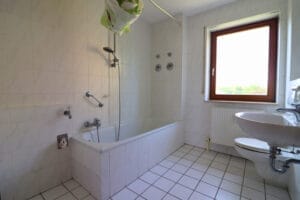 Badezimmer mit Fenster, Badewanne und Waschmaschinenanschluss