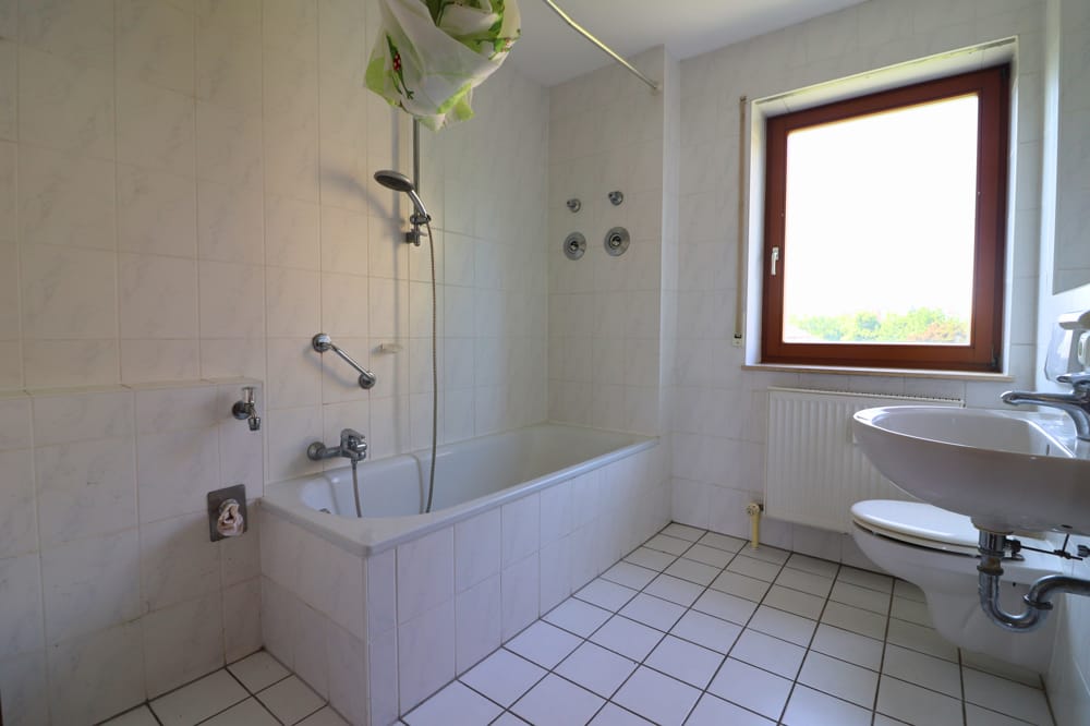 Badezimmer mit Fenster, Badewanne und Waschmaschinenanschluss